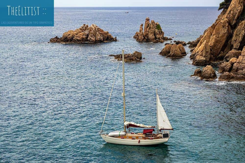 a sailboat in the ocean with rocks in the background
