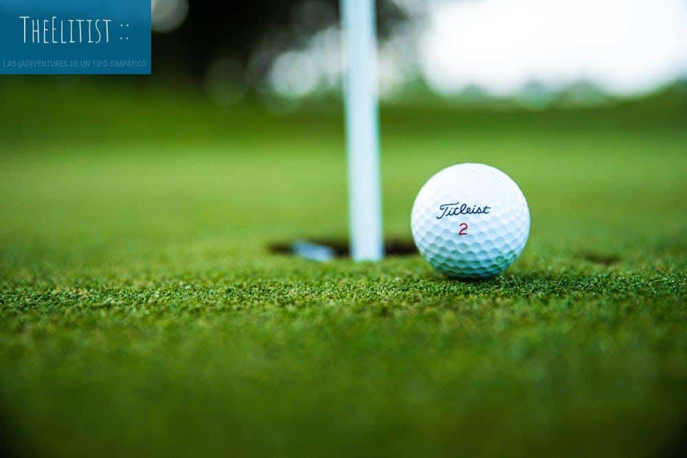 A close-up shot of a Titleist golf ball close to the hole on a green golf course.