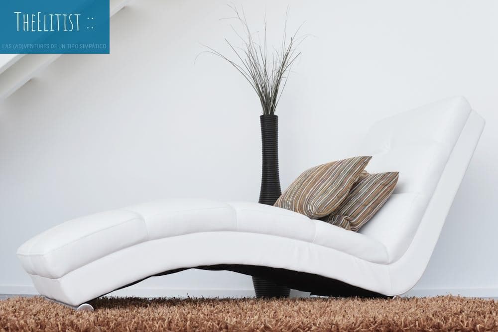 Elegant white lounge chair with cushions on plush carpet, perfect for relaxation.
