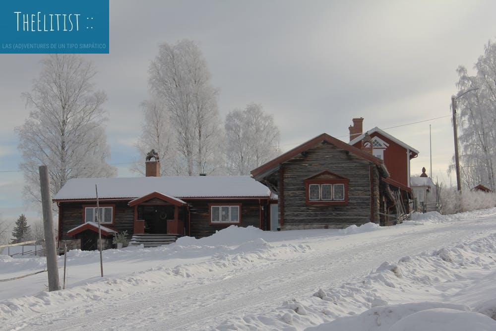 A picturesque winter scene of a traditional wooden cottage in a snowy Swedish landscape.