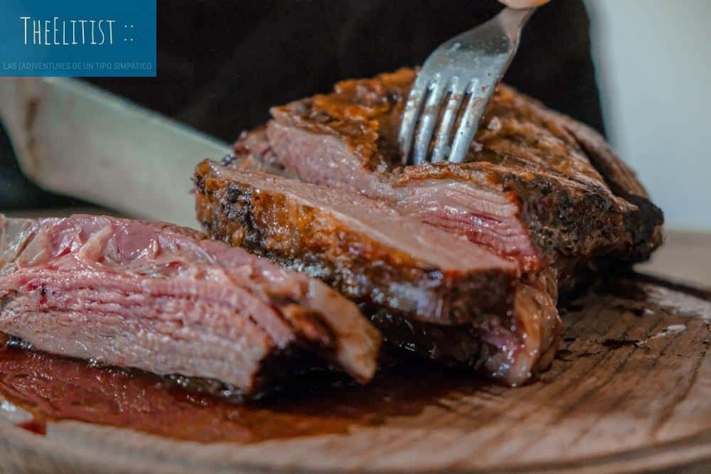 person slicing a meat on brown wooden board