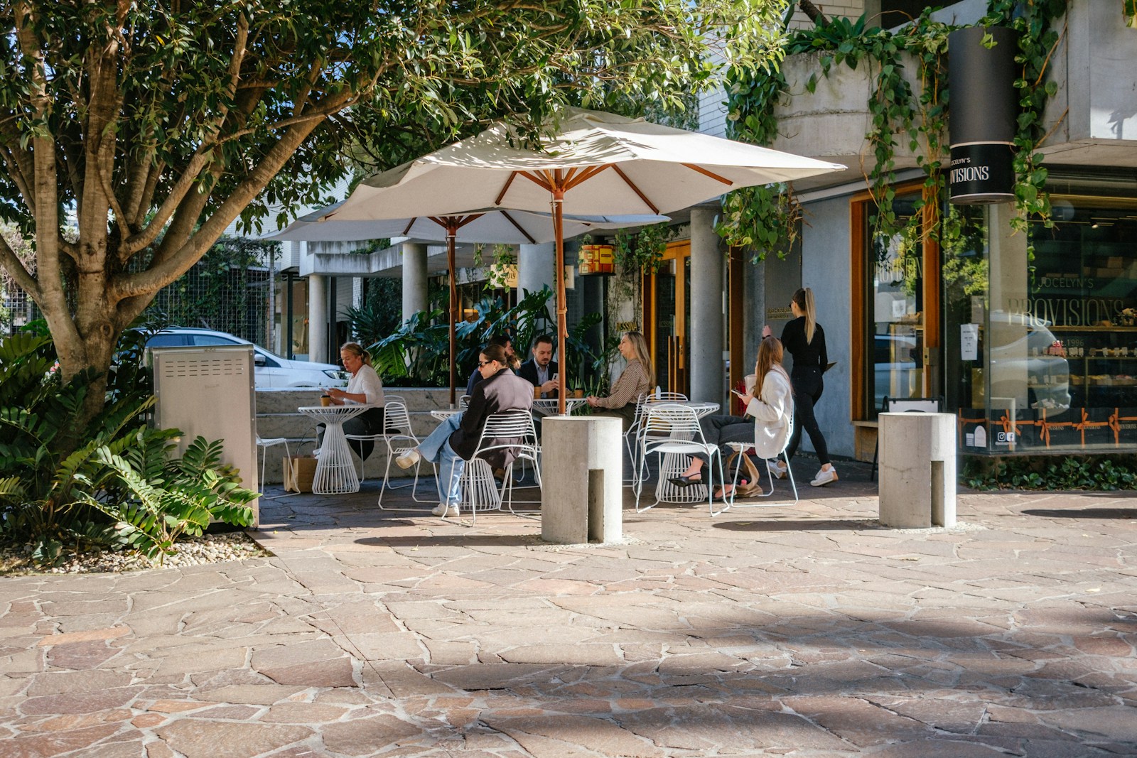 Terraza de un café con sombrillas y gente charlando al sol